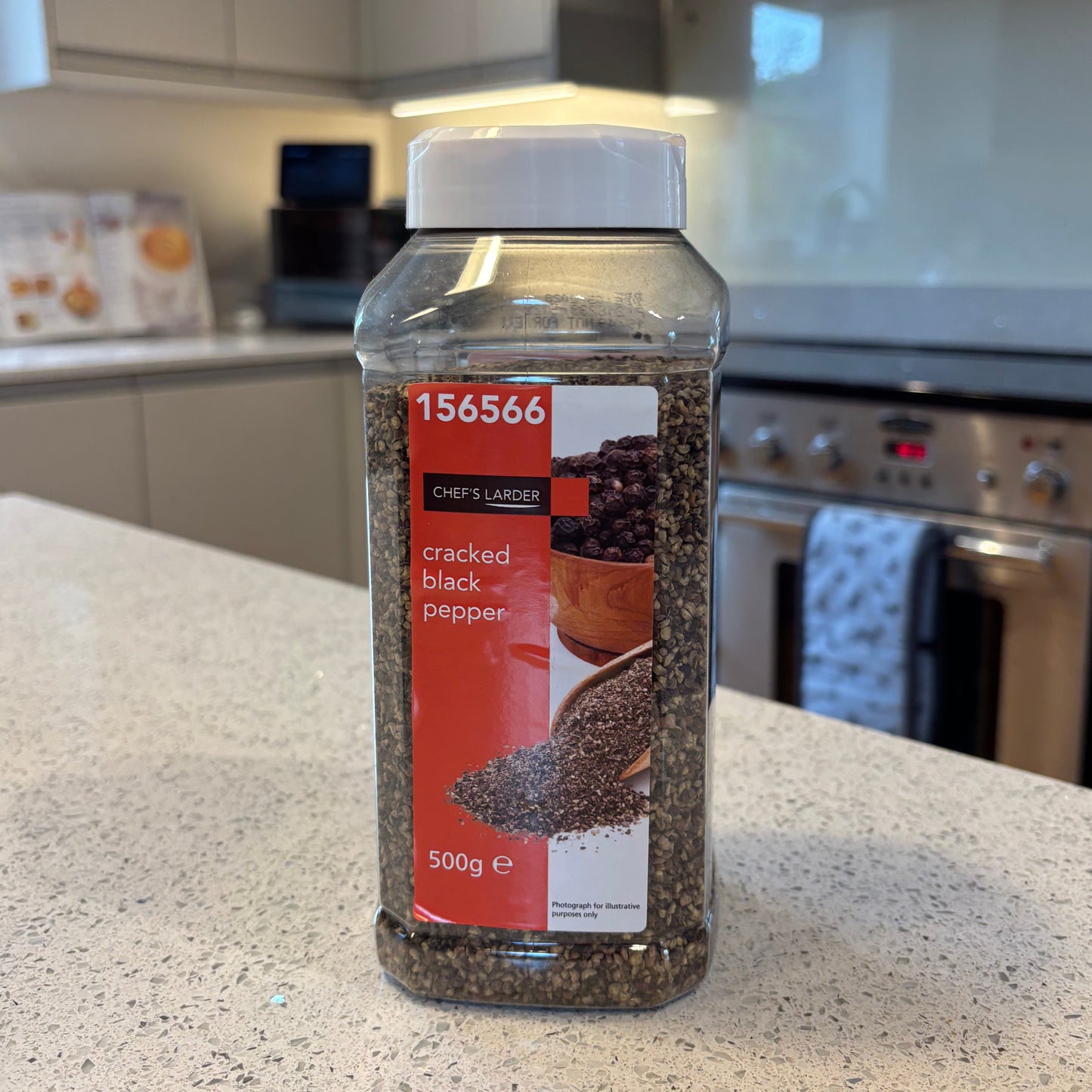 Bottle of Chef's Larder cracked black pepper on a kitchen counter with a blurred background