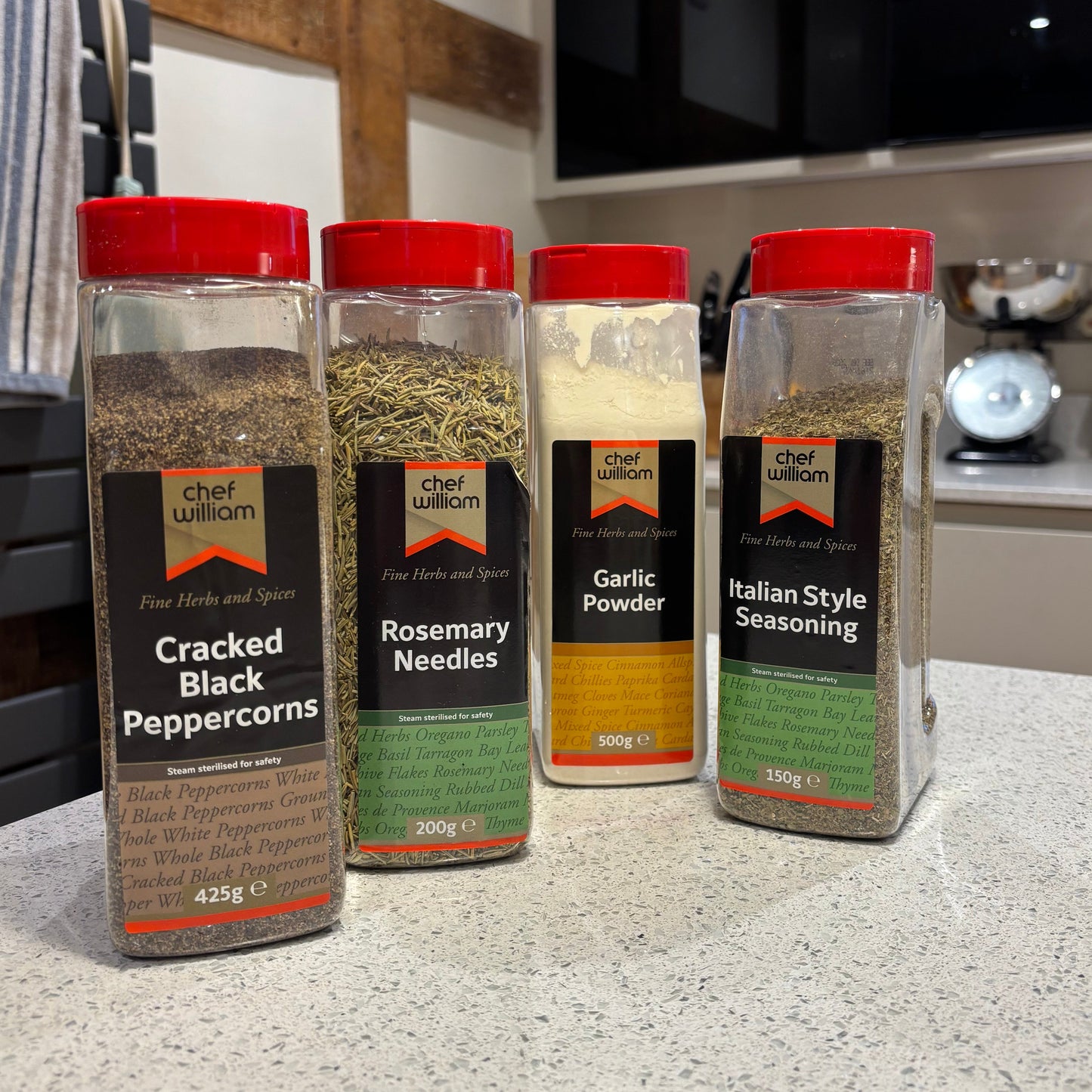 Chef William spice containers for Italian seasoning stacked on a kitchen counter with a blurred background