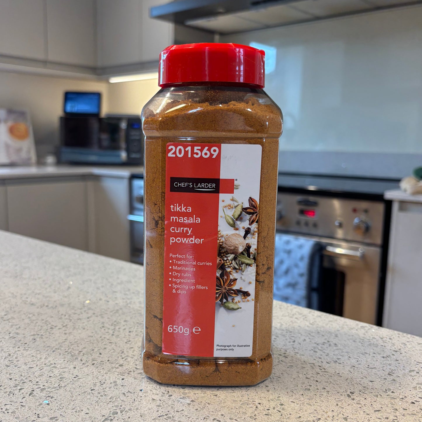 Spice bottle of Chef's Larder tikka masala curry powder on a kitchen counter with a blurred background