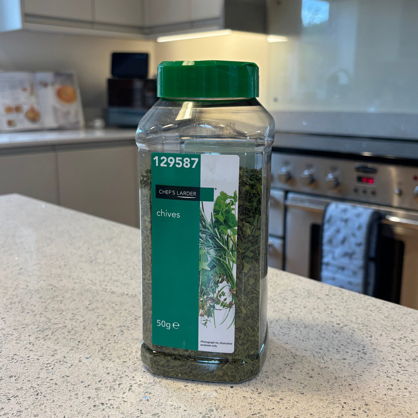 Resealable pot of Chef's Larder dried chives with a green label on a kitchen counter