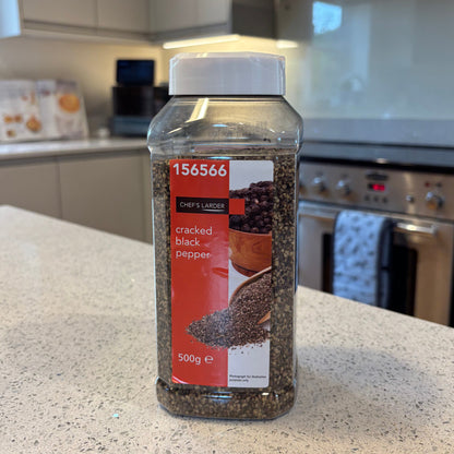 Bottle of Chef's Larder cracked black pepper on a kitchen counter with a blurred background