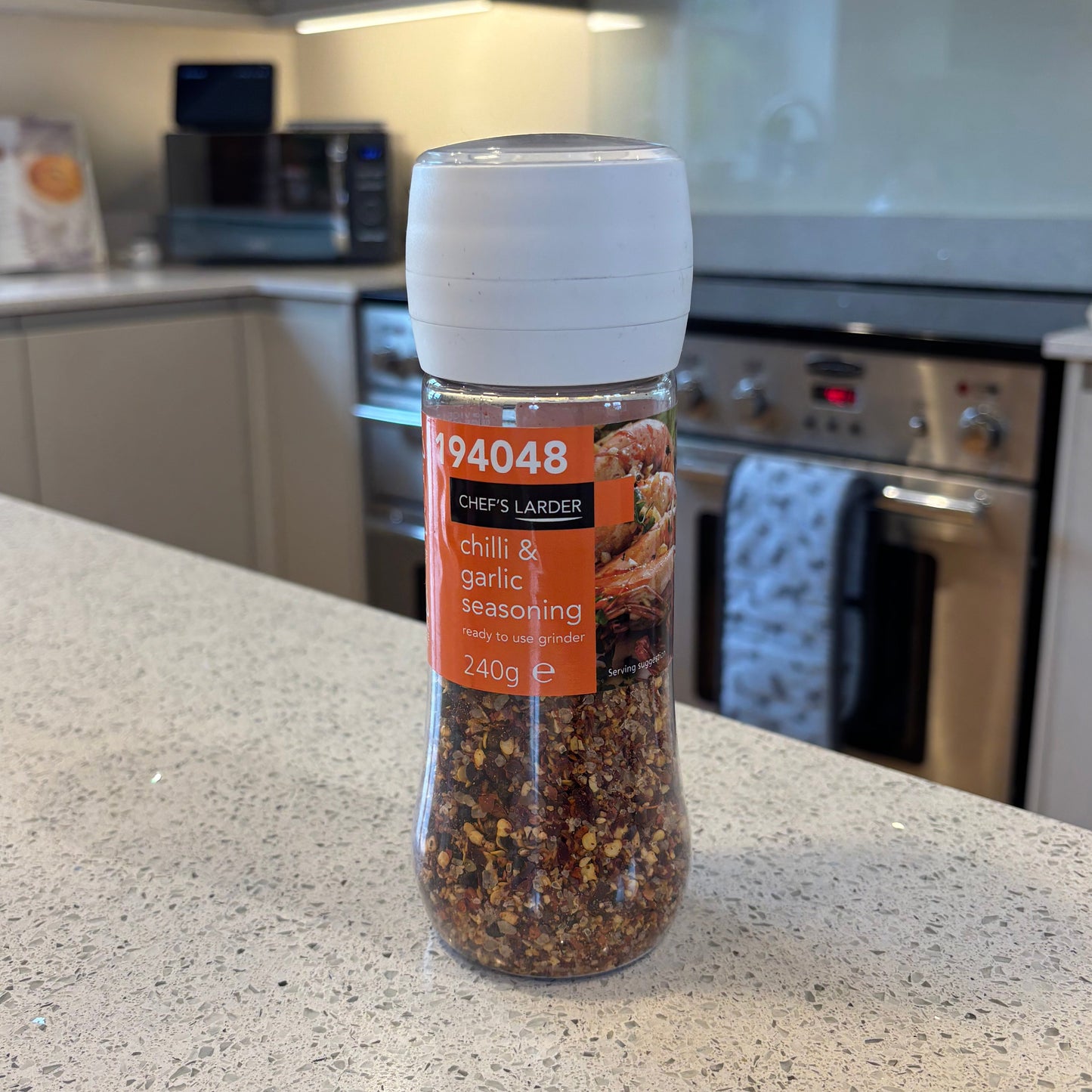 Spice Grinder of Chef's Larder Chilli & Garlic Seasoning on a kitchen counter with a blurred background