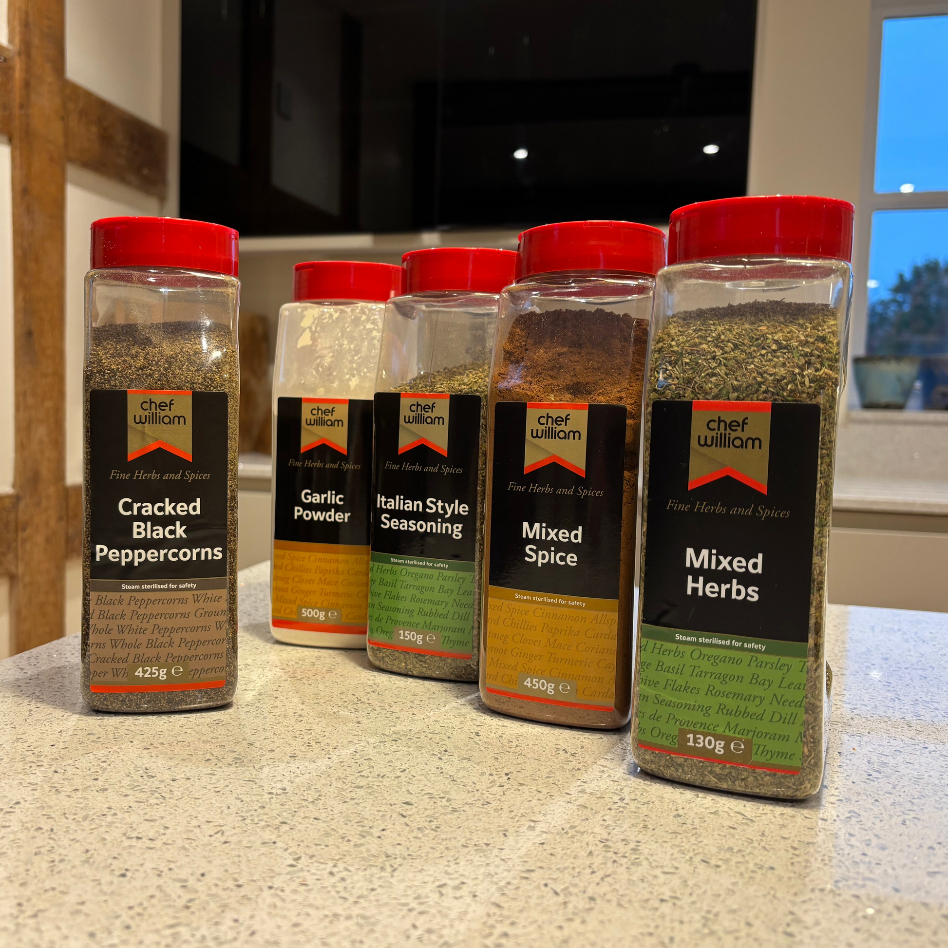 Five bottles of Everyday Essentials Chef William spices on a kitchen counter.